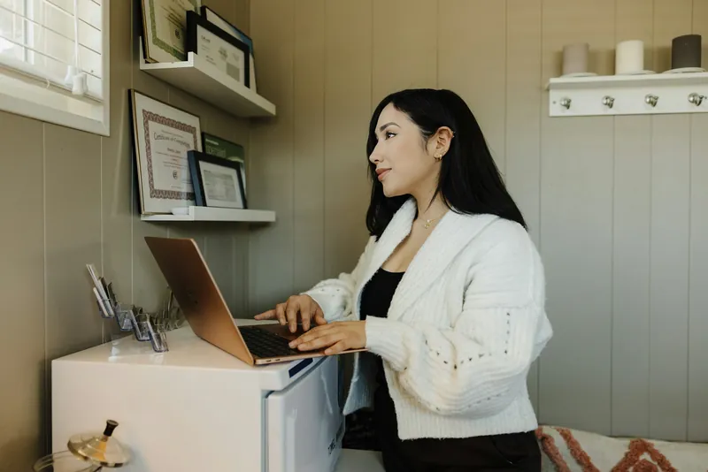 Een ondernemer werkt staand aan een laptop in haar zaak